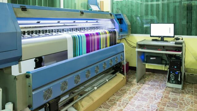 Technician printing vinyl multi color cmyk on large inkjet printer in workplace