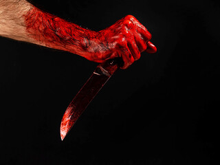 Man holding knife with bloody hand on black background. 