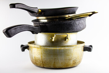 Dirty old utensils in a stack of metal on a white background, isolated. Dirty pots, frying pans for cooking.
