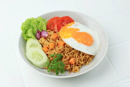 Indomie Goreng, Instant Fried Noodle Popular from Indonesia. Served with Carrot, Cucumber, Tomato, Shallot, Lettuce, and Fried Egg