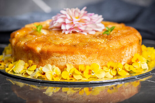 Home-made upside-down pineapple cake with mint and decorative edible flowers.