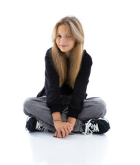 Fototapeta premium Portrait of pretty long hair girl isolated on white background. Teen woman sitting cross legged and smile into camera.