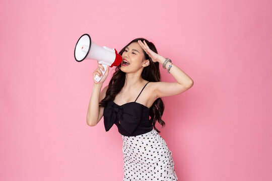 Asian Woman Smiling Face Holding Megaphone Shouting, Posing Isolated On Pink Pastel Wall, Photo Studio Background, With Copy Space