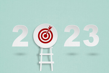 2023 year with red target dartboard paper cut and ladder for setup business target concept © Ratana21