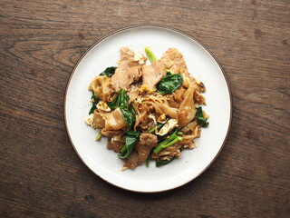 Top view dish of PAD SEE EW, Thai stir-fried flat noodles with dark soy sauce on wood