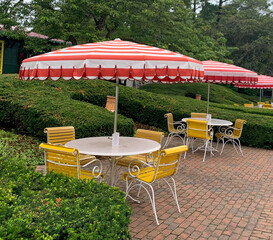 yellow picnic table with striped red umbrellas 