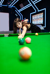 A sexy woman in a black halter dress at a pool table