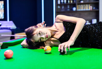 A sexy woman in a black halter dress at a pool table