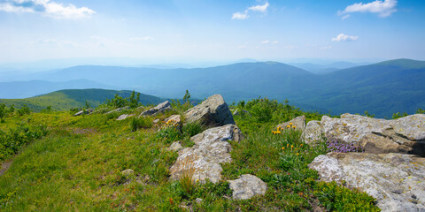 carpathian countryside in summer. mountain landscape with view in to the distant ridge and alpine valley. stones on the grassy meadow in the afternoon light