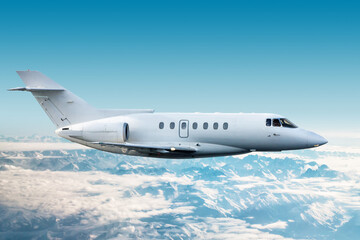 Fototapeta premium White modern corporate aircraft flies over snow-covered mountains