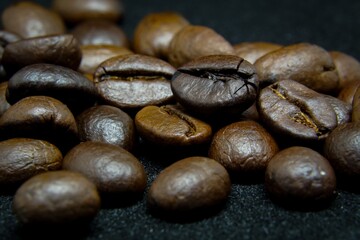 The way coffee beans lay on a black background, elegant and delicious coffee beans and the aroma of morning coffee.