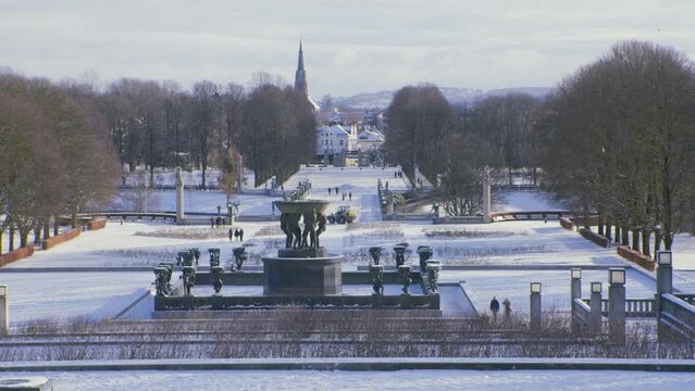 Frogner park in Oslo, Norway, wide landscape with construction work, tractor, sculptures, city in background