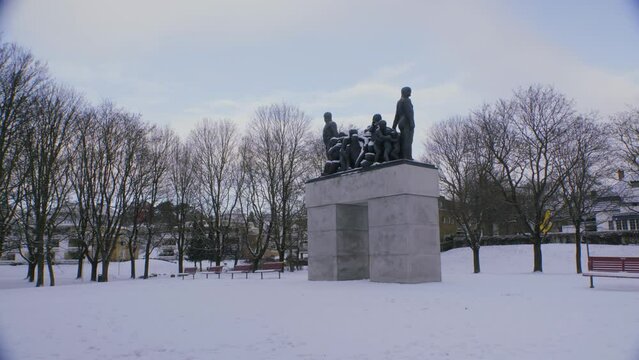 Stone statue at Frogner park, Vigeland exhibit with trees on a sunny with clouds, snowy winter day