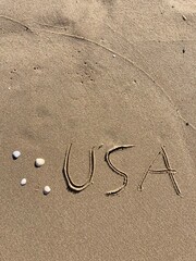 Fototapeta na wymiar on the beach is carved with letters in the smooth sand the writing USA