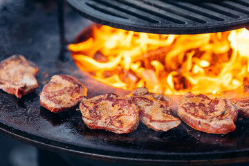Street food concept. Chef cook prepares Beef steak is fried on open fire outdoor grill in shape of circle
