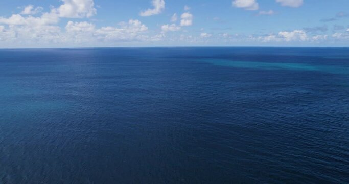 Blue Pacific ocean waters of Hawaii below cloudy sky, drone view.
