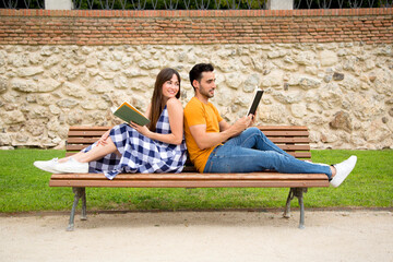 Romantic scene of lovers reading books sitting back to back in a park