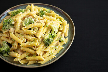 Homemade Penne Alfredo Pasta with Chicken and Broccoli on a Plate on a black background, side view. Copy space.