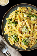 Homemade Penne Alfredo Pasta with Chicken and Broccoli on a Plate on a black background, top view. Close-up.
