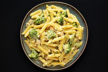 Homemade Penne Alfredo Pasta with Chicken and Broccoli on a Plate on a black background, top view. Overhead, flat lay, from above.