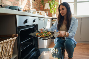 Shot of woman dressed in casual attire baking home made pizza for her friends.