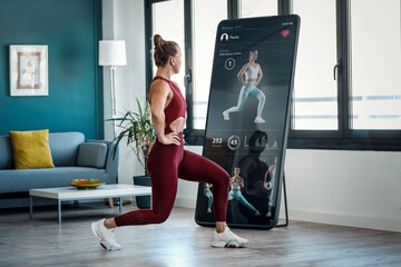 Powerful woman doing gymnastics exercises through a mobile app at home.