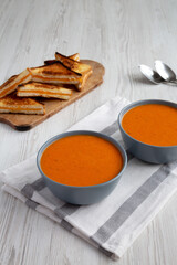 Homemade Tomato Soup with Grilled Cheese on a white wooden background, side view.