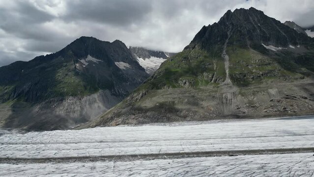 Aletch Glacier Hiking Path. Drone panning on glacier surface, high mountains on the background