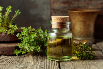 Bottle of thyme essential oil with fresh thyme twigs.