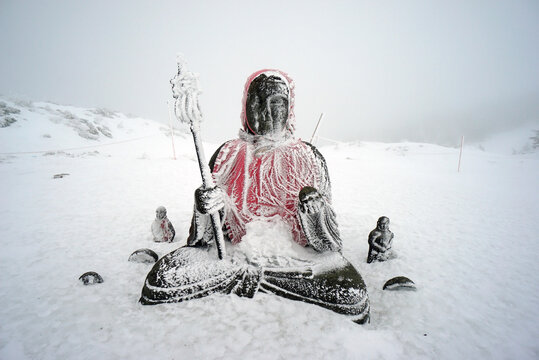 A snowstorm covers the Buddha image on the top of the mountain in winter.   