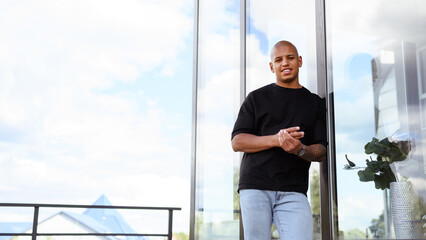 Banner shot of african american man smiling at camera on balcony