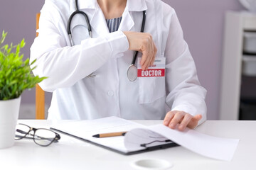 A doctor in a white coat sits in the office at the table