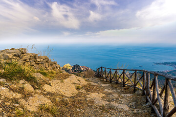 Fototapeta premium mountain landscape with a hiking trail leading to a mountain town and beautiful blue seashore far away