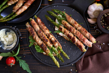 Tasty breakfast - toasts with cream cheese and Asparagus wrapped with bacon and spices on a plate