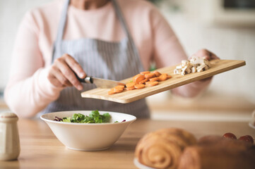 Close up of females hands holding cutting board with cut veggies
