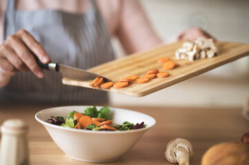 Obraz na płótnie Canvas Close up of females hands holding cutting board with cut veggies