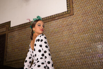 Beautiful teenage woman dancing flamenco with white dress and black polka dots doing flamenco...