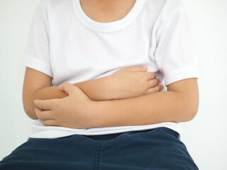 Kid boy with stomach ache on white background. Health concept. Closeup photo, blurred.