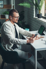 Business man writing on paper notebook on office table during working from home, using tablet and mobile phone. Business portrait. Education concept. Distance