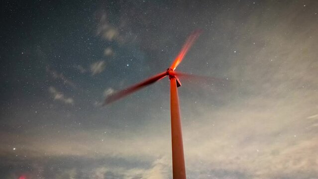 1080p timelapse in a wind farm produces electric named green energy from wind with night sky stars and milkyway clouds moving