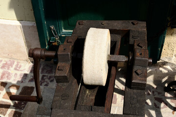 old style round grindstone wheel. knife sharpening tool set in wood frame. vintage equipment. rusty...