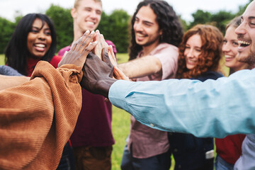 Group of multi-ethnic young adult friends bonding together joining hands taking high five outdoors...