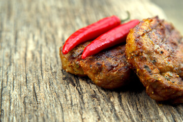 Meat steak cooked on the barbecue. Grilled fresh meat steak with spices and red pepper. Ready steak on the table with tomatoes and peppers. The concept of food, restaurants, traditional cuisine.
