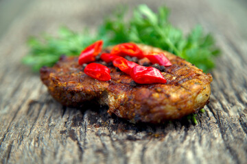 Meat steak cooked on the barbecue. Grilled fresh meat steak with spices and red pepper. Ready steak on the table with tomatoes and peppers. The concept of food, restaurants, traditional cuisine.