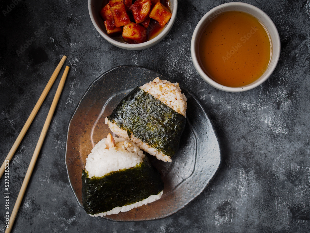 Wall mural Onigiri Japanese traditional food, steamed rice in triangle shape wrap with seaweed top view on grey background