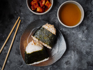 Onigiri Japanese traditional food, steamed rice in triangle shape wrap with seaweed top view on grey background