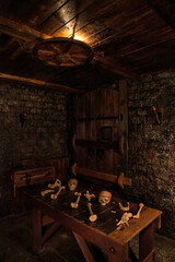 Dark background at mystical interior of medieval castle room with wooden table with skulls and bones against an ancient stone wall with door. Scary backgrounds for Halloween. Copy space, text place