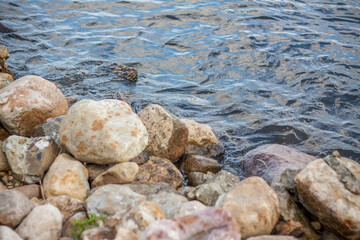 Wallpaper with stones by the river and water. Take a walk in the park on a summer day and admire the beautiful scenery. Selective focus, wallpaper.