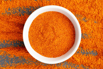 Red chili pepper spice in ceramic bowl on scattered red chili background. Macro. Flat lay. Vegetarian food concept