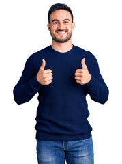 Young handsome man wearing casual clothes success sign doing positive gesture with hand, thumbs up smiling and happy. cheerful expression and winner gesture.